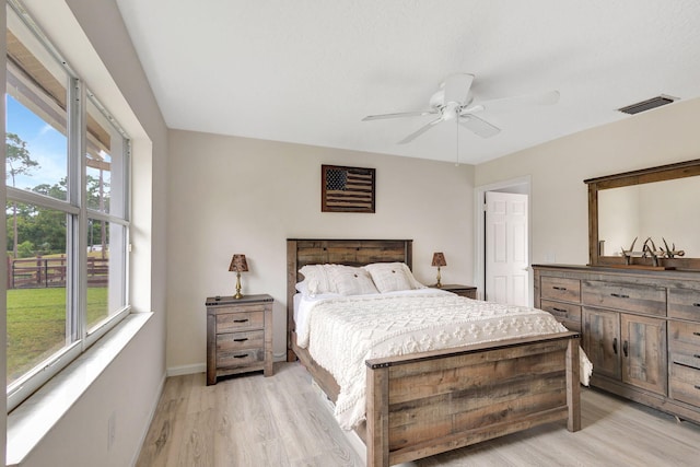 bedroom featuring multiple windows, light hardwood / wood-style floors, and ceiling fan