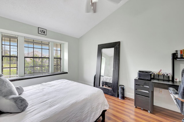 bedroom featuring lofted ceiling, a textured ceiling, wood-type flooring, and ceiling fan