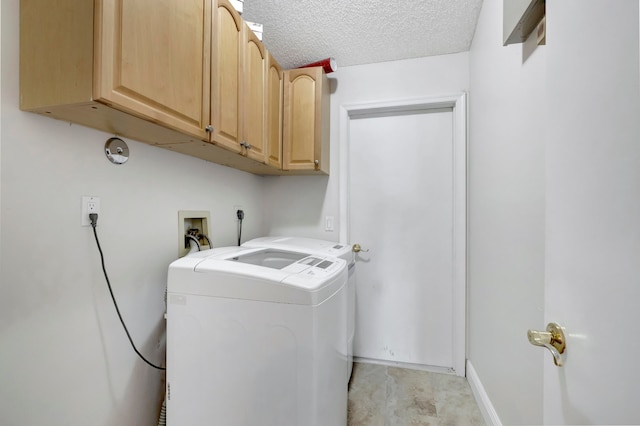 laundry room with a textured ceiling, separate washer and dryer, and cabinets