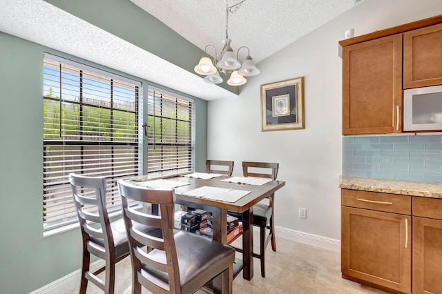 dining space featuring a textured ceiling, vaulted ceiling, and a chandelier