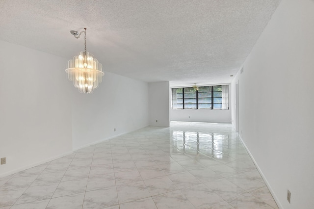 empty room featuring a notable chandelier and a textured ceiling