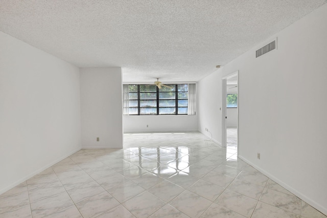 spare room with a textured ceiling, light tile patterned floors, and ceiling fan