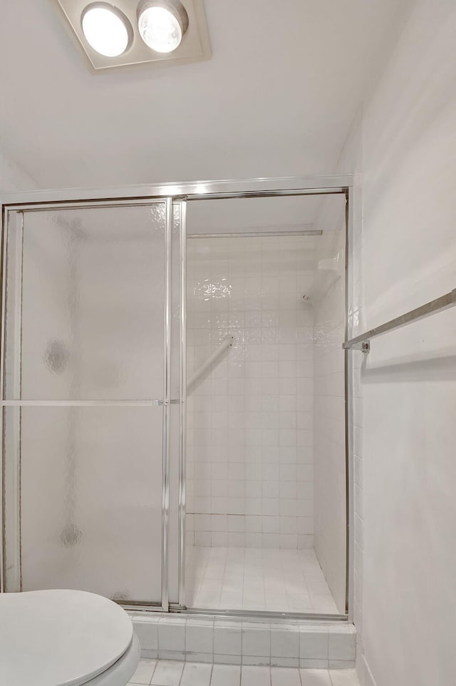 bathroom featuring tile patterned floors, toilet, and an enclosed shower