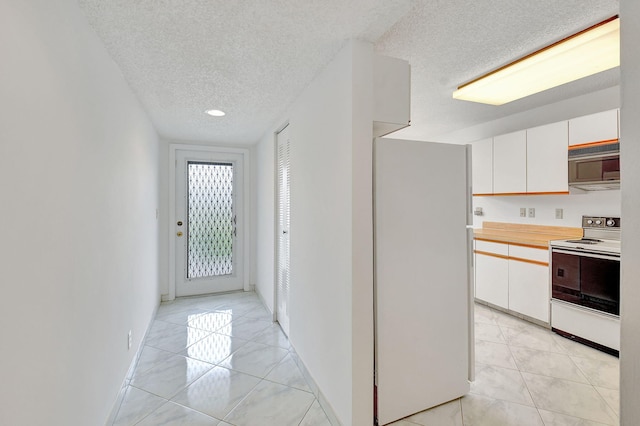 kitchen featuring light tile patterned floors, white refrigerator, white cabinets, a textured ceiling, and electric stove