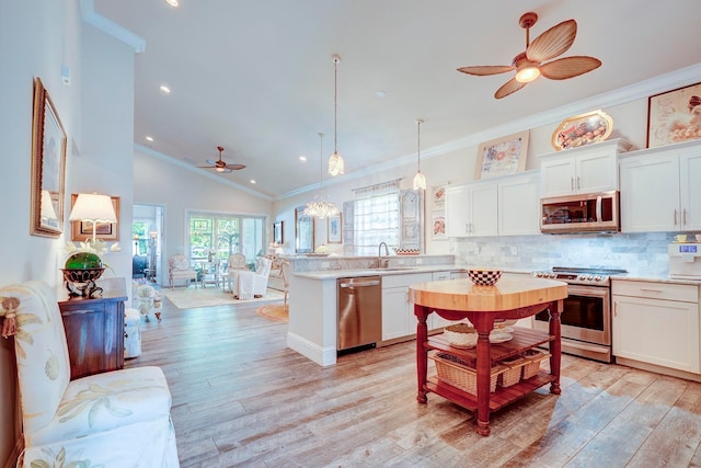 kitchen with appliances with stainless steel finishes, hanging light fixtures, white cabinetry, and ceiling fan