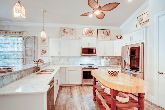 kitchen with appliances with stainless steel finishes, light hardwood / wood-style flooring, sink, and hanging light fixtures