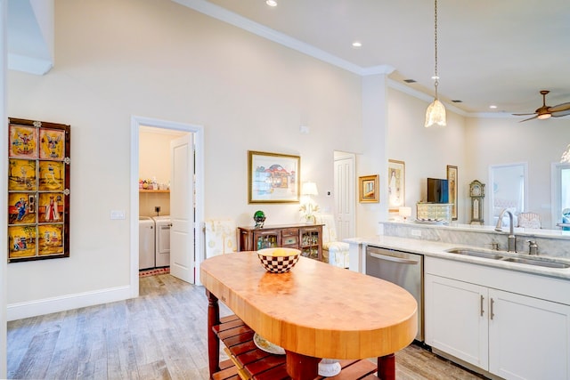 kitchen with dishwasher, light wood-type flooring, white cabinets, washer and dryer, and a towering ceiling