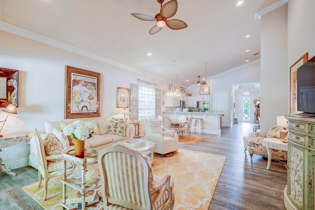 living room with crown molding, wood-type flooring, and ceiling fan with notable chandelier