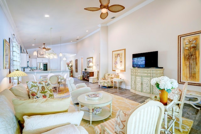 living room featuring a towering ceiling, ceiling fan, ornamental molding, and hardwood / wood-style floors