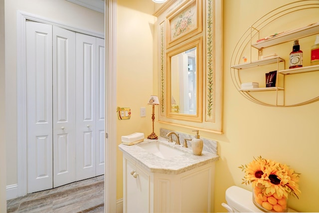 bathroom with vanity, toilet, crown molding, and wood-type flooring