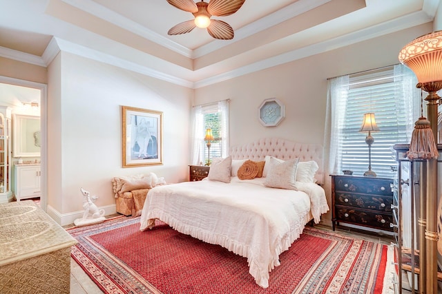 bedroom featuring ornamental molding, ensuite bathroom, a raised ceiling, and ceiling fan