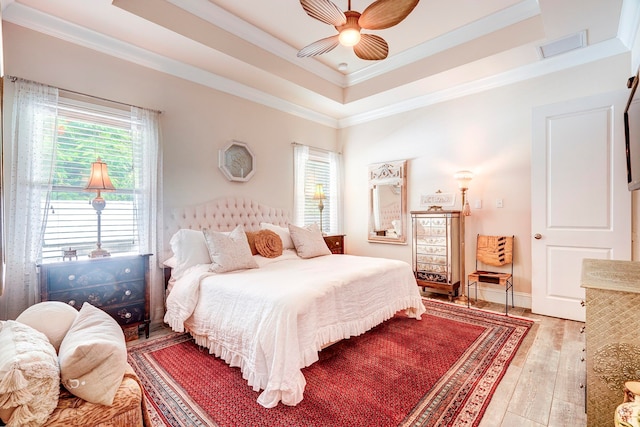 bedroom with ceiling fan, crown molding, a raised ceiling, and hardwood / wood-style floors