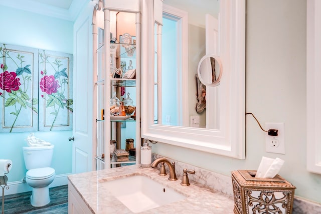 bathroom with toilet, crown molding, vanity, and wood-type flooring