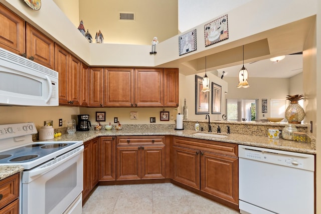 kitchen featuring light stone countertops, sink, pendant lighting, white appliances, and light tile patterned floors