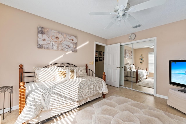 bedroom with ceiling fan, a closet, light tile patterned floors, and a textured ceiling