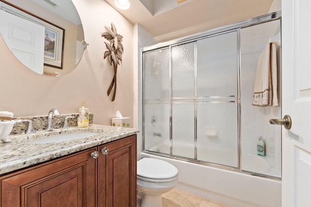 full bathroom with tile patterned floors, combined bath / shower with glass door, toilet, and vanity