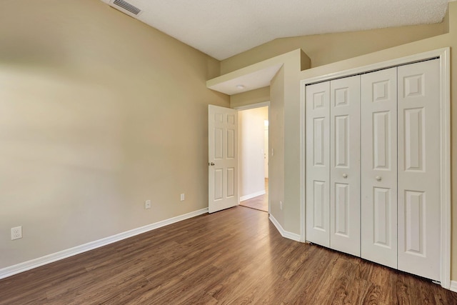 unfurnished bedroom featuring dark wood-type flooring, a closet, and lofted ceiling