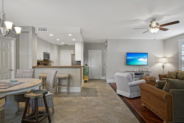 living room with ceiling fan with notable chandelier