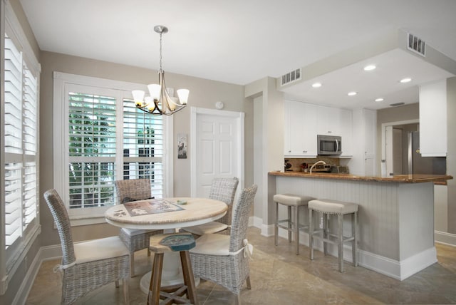 dining area featuring a wealth of natural light, sink, and a notable chandelier