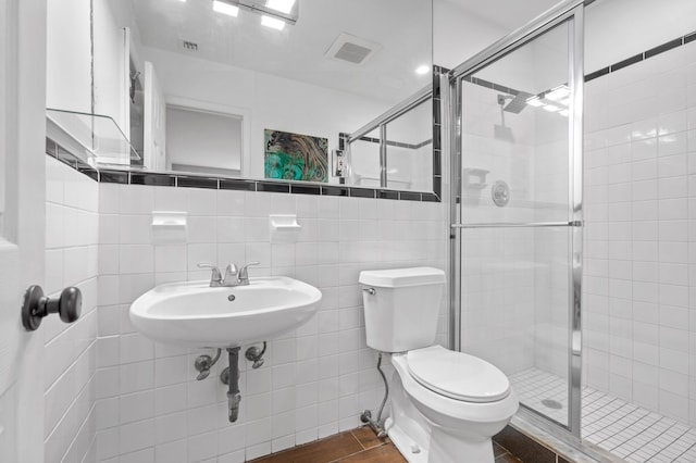 bathroom featuring wood-type flooring, a shower with door, tile walls, and toilet