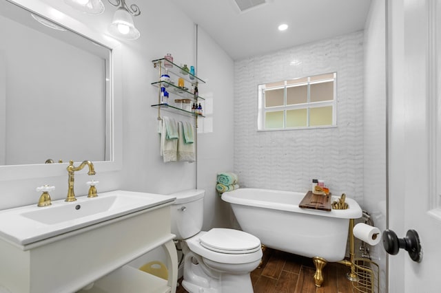 bathroom featuring wood-type flooring, a tub to relax in, toilet, and vanity