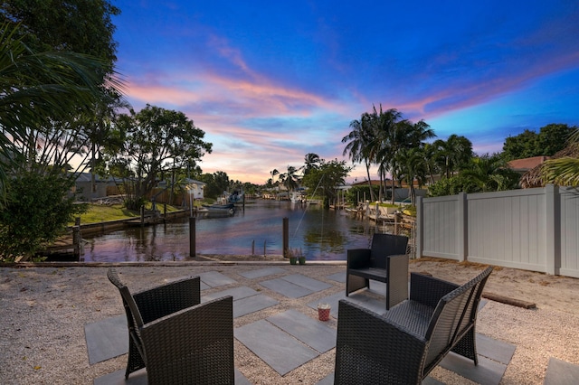 patio terrace at dusk with a water view and a boat dock