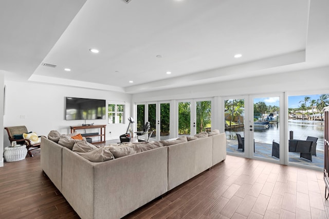 living room featuring dark wood-type flooring, french doors, and a tray ceiling