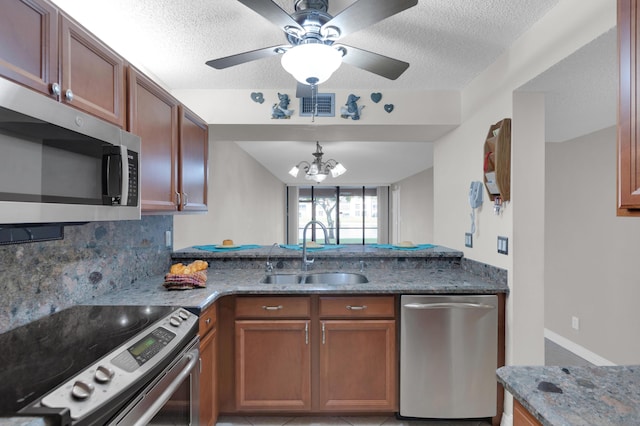 kitchen with sink, a textured ceiling, appliances with stainless steel finishes, stone counters, and decorative backsplash