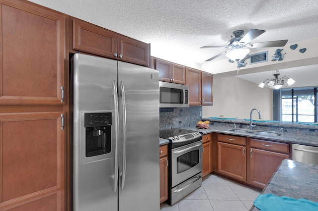 kitchen with sink, tasteful backsplash, a textured ceiling, light tile patterned floors, and appliances with stainless steel finishes