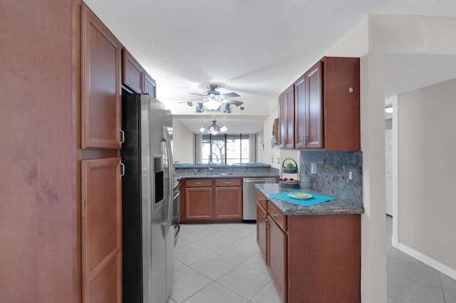 kitchen with sink, light tile patterned floors, appliances with stainless steel finishes, a textured ceiling, and decorative backsplash