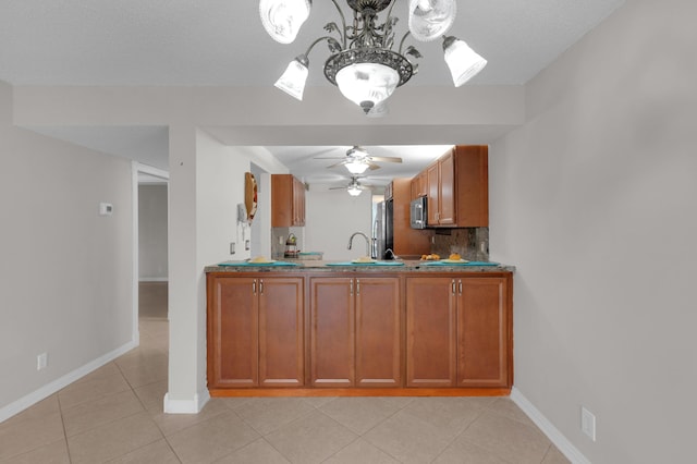 kitchen with tasteful backsplash, light tile patterned floors, ceiling fan with notable chandelier, and appliances with stainless steel finishes