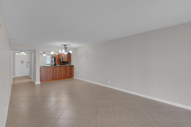 unfurnished living room with light tile patterned floors, ceiling fan with notable chandelier, and a textured ceiling