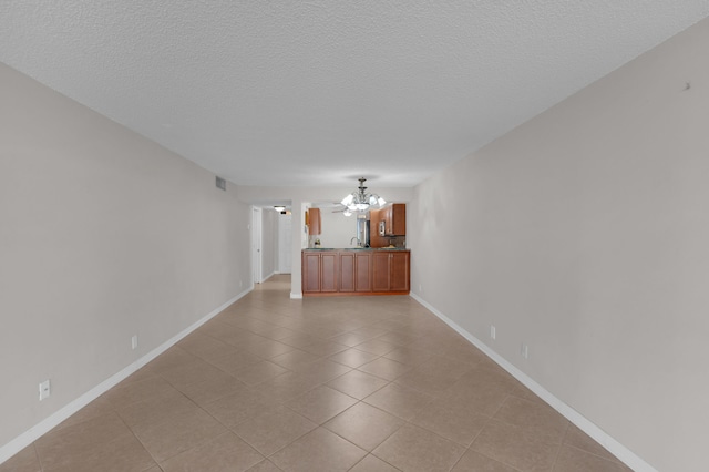 unfurnished room featuring a notable chandelier, light tile patterned floors, and a textured ceiling