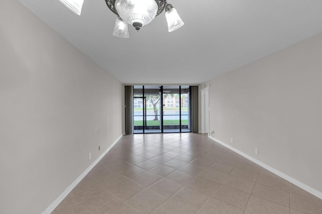 spare room featuring a wall of windows, a skylight, a textured ceiling, and light tile patterned floors