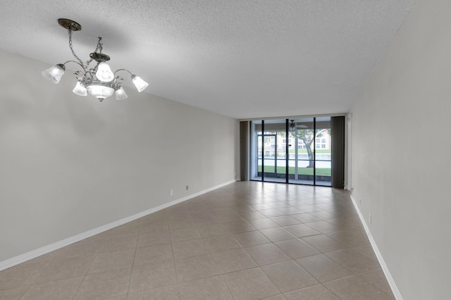 tiled spare room with floor to ceiling windows, a textured ceiling, and a chandelier