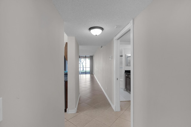 corridor with light tile patterned flooring and a textured ceiling