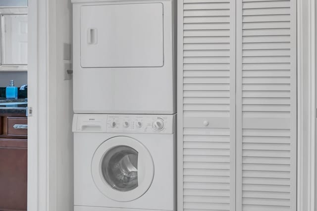 laundry room featuring stacked washer / drying machine and sink