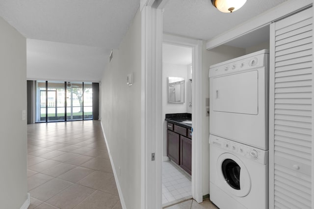 washroom featuring stacked washer / drying machine, a textured ceiling, and light tile patterned floors