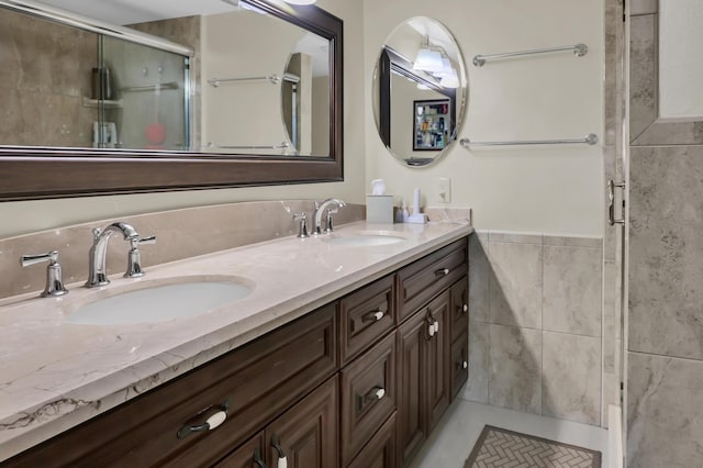 bathroom with vanity, a shower with shower door, and tile walls