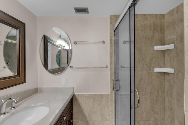 bathroom featuring vanity, a shower with shower door, and tile walls