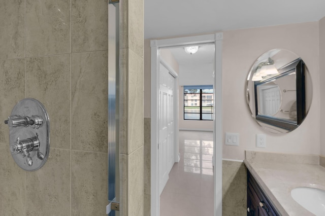 bathroom featuring tile walls, vanity, a shower with shower door, and tile patterned floors