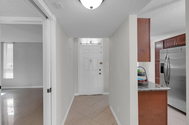 foyer with light tile patterned floors and a textured ceiling