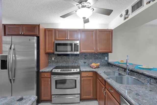 kitchen with appliances with stainless steel finishes, light stone countertops, sink, and decorative backsplash