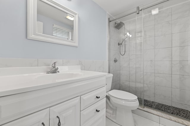 bathroom featuring toilet, a shower with shower door, vanity, and tile walls