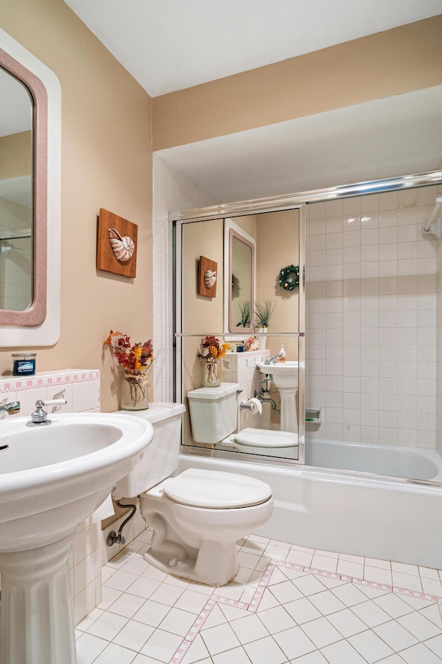 bathroom featuring combined bath / shower with glass door, toilet, and tile patterned flooring