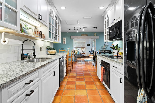 kitchen featuring sink, black appliances, white cabinets, and tasteful backsplash