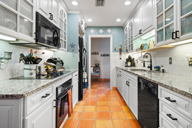 kitchen with white cabinets, light stone counters, backsplash, black appliances, and sink