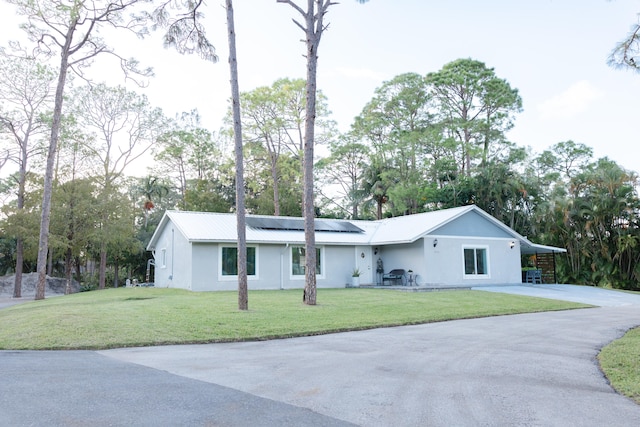 ranch-style house with solar panels and a front lawn