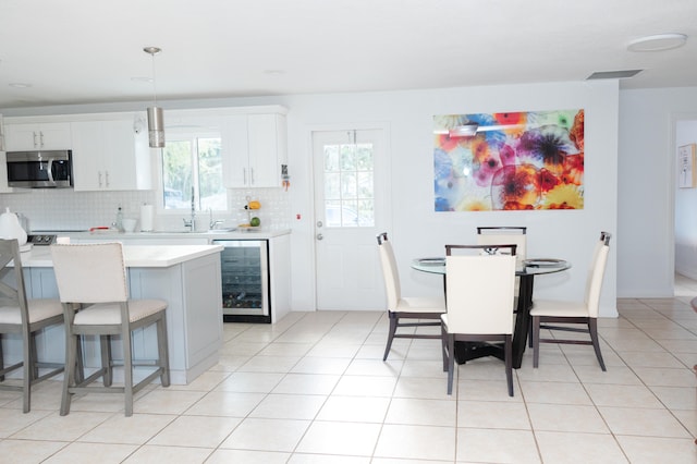 kitchen featuring decorative backsplash, white cabinetry, hanging light fixtures, and beverage cooler