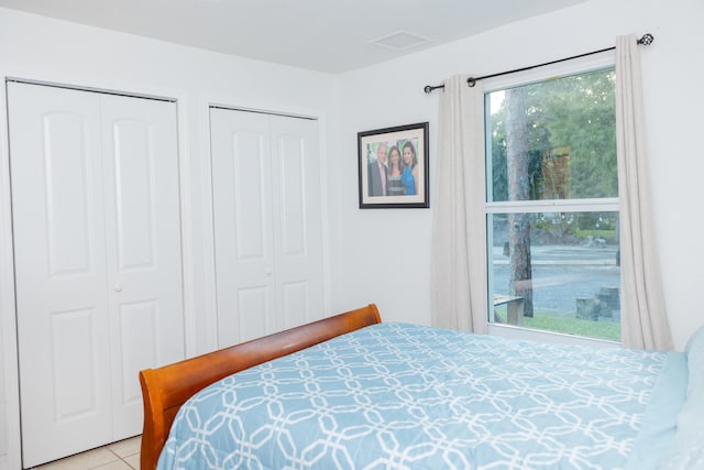 bedroom with multiple closets and light tile patterned floors